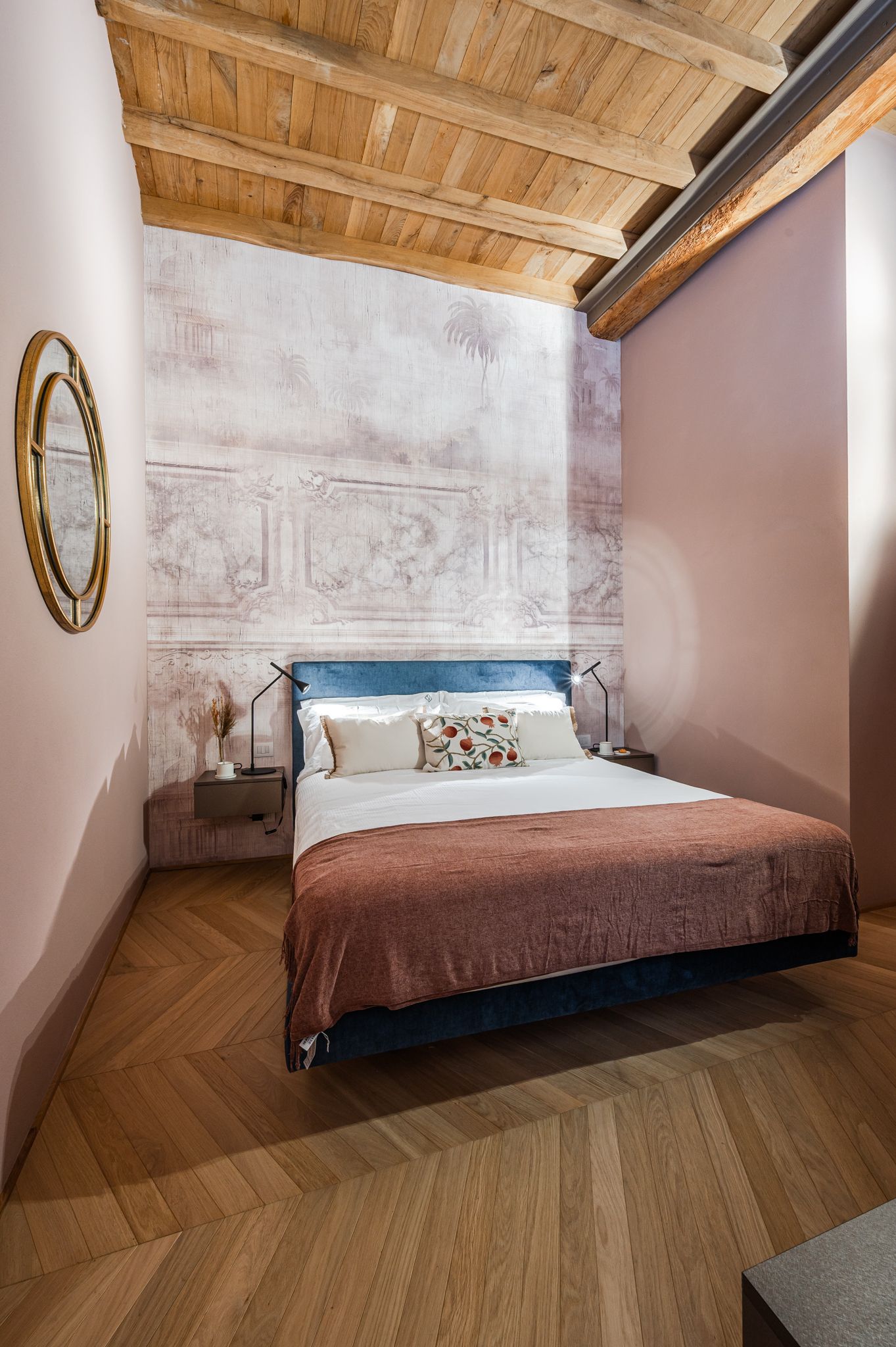 Camera da letto con testiera in velluto blu e carta da parati effetto affresco antico