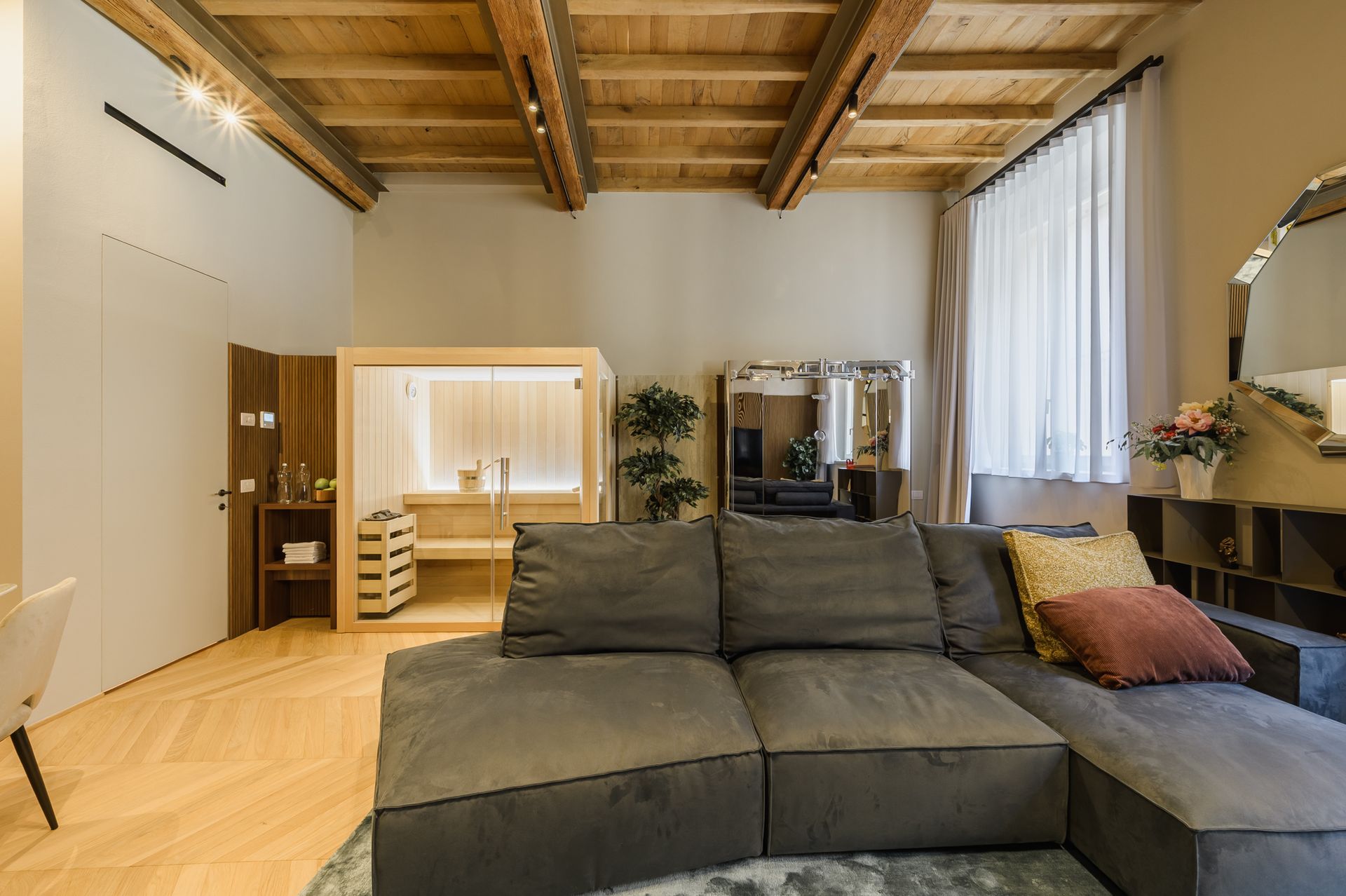 Salotto-wellness: divano, sauna illuminata e Kinesis Technogym nella stessa inquadratura
