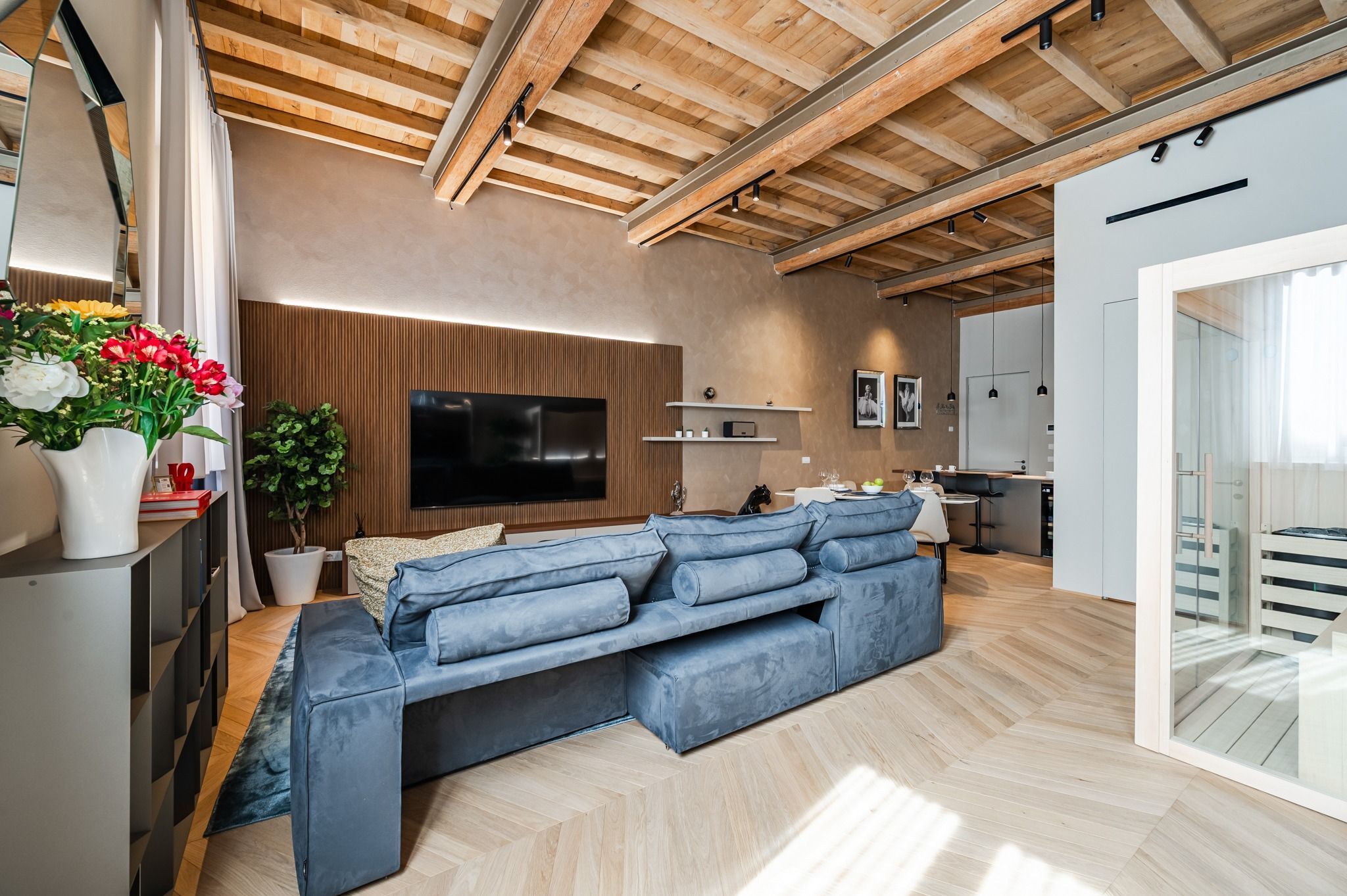 Living con divano blu, travi a vista e sauna in fondo